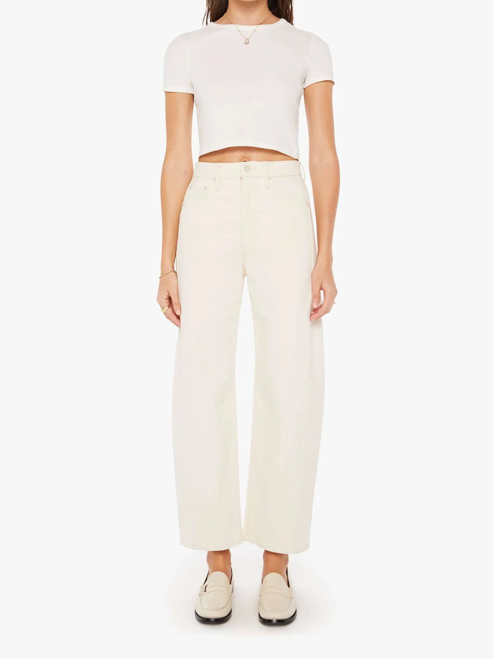 Woman wearing a white crop top and cream-colored pants on a white background
