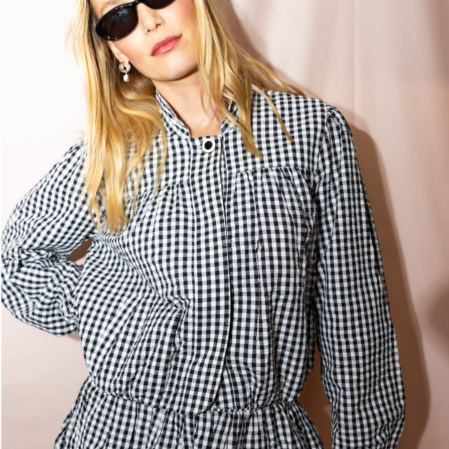 Woman wearing a black and white checkered dress against a plain background