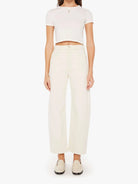 Woman wearing a white crop top and cream-colored pants on a white background