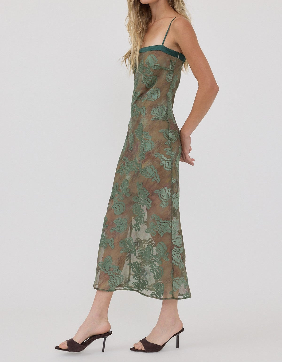 Woman wearing a green floral slip dress on a white background