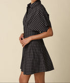 Woman wearing a black and white checkered dress against a beige background