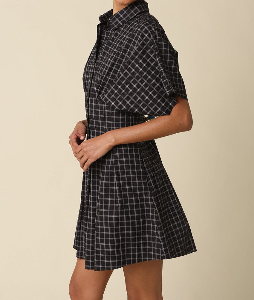 Woman wearing a black and white checkered dress against a beige background