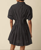Person wearing a black and white checkered dress against a beige background