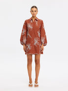 Woman wearing a brown floral dress on a white background