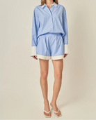 Woman wearing a blue and white striped shirt and shorts on a beige background