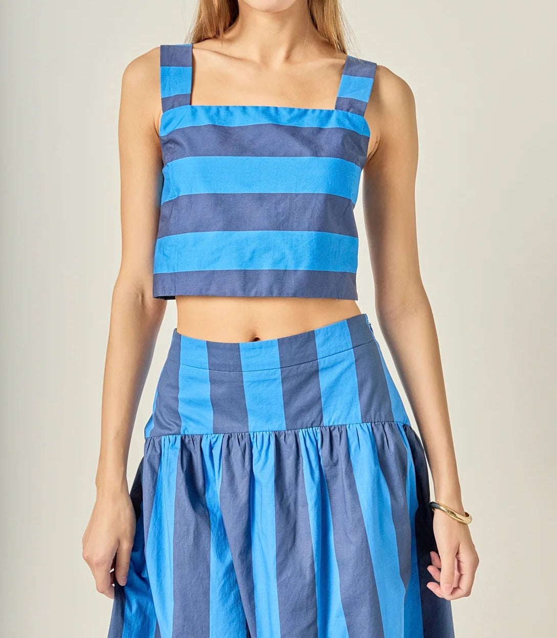 Woman wearing a blue and white striped outfit on a plain background