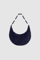 Navy blue suede handbag with a decorative handle on a light gray background