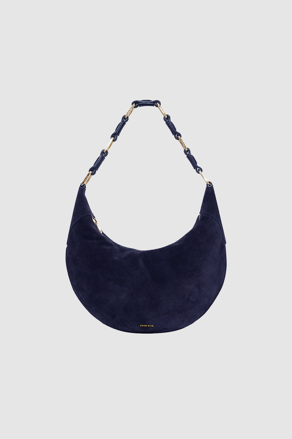 Navy blue suede handbag with a decorative handle on a light gray background