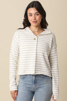 Woman wearing a striped shirt and jeans against a beige background
