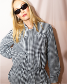 Woman wearing a black and white checkered dress against a plain background