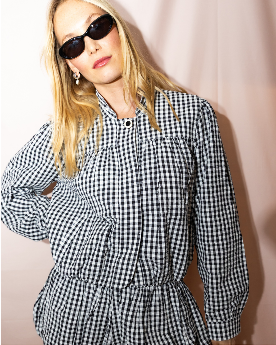 Woman wearing a black and white checkered dress against a plain background