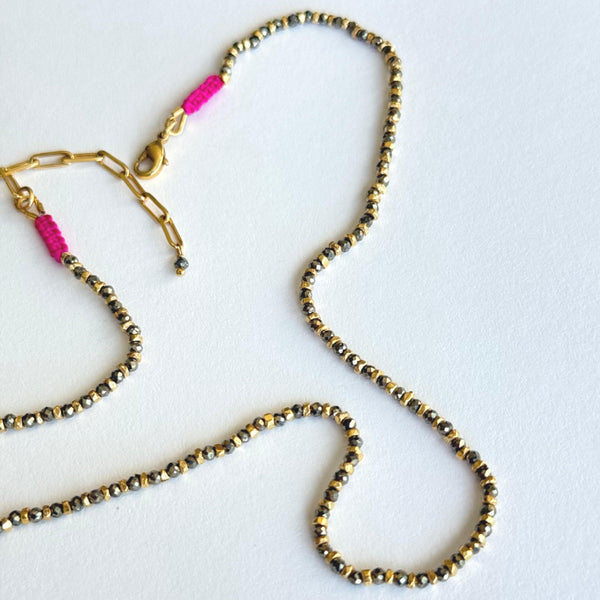 Beaded lanyard with gold and black beads and pink accents on a white background