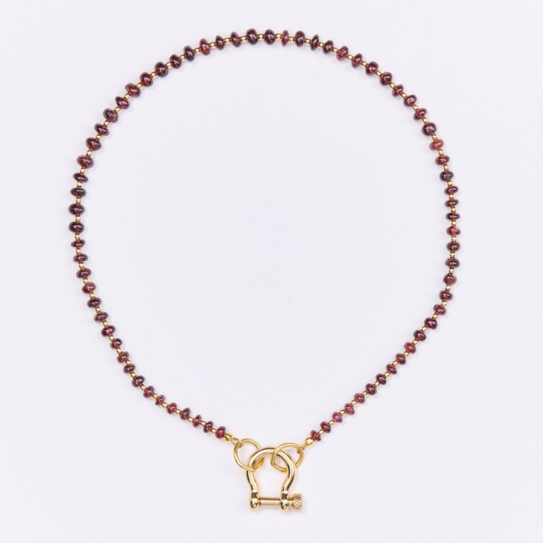 Necklace with red beads and a gold clasp on a white background