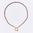 Necklace with red beads and a gold clasp on a white background