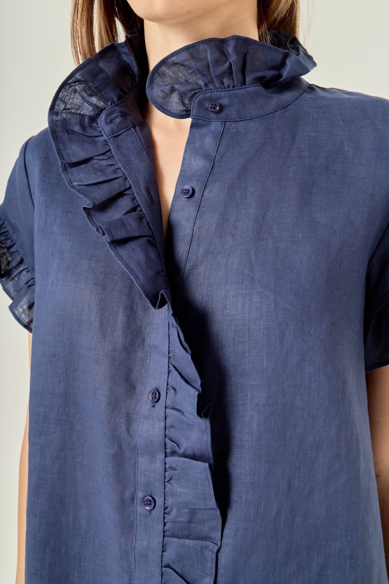 Navy blue shirt with ruffled collar and cuffs on a plain background