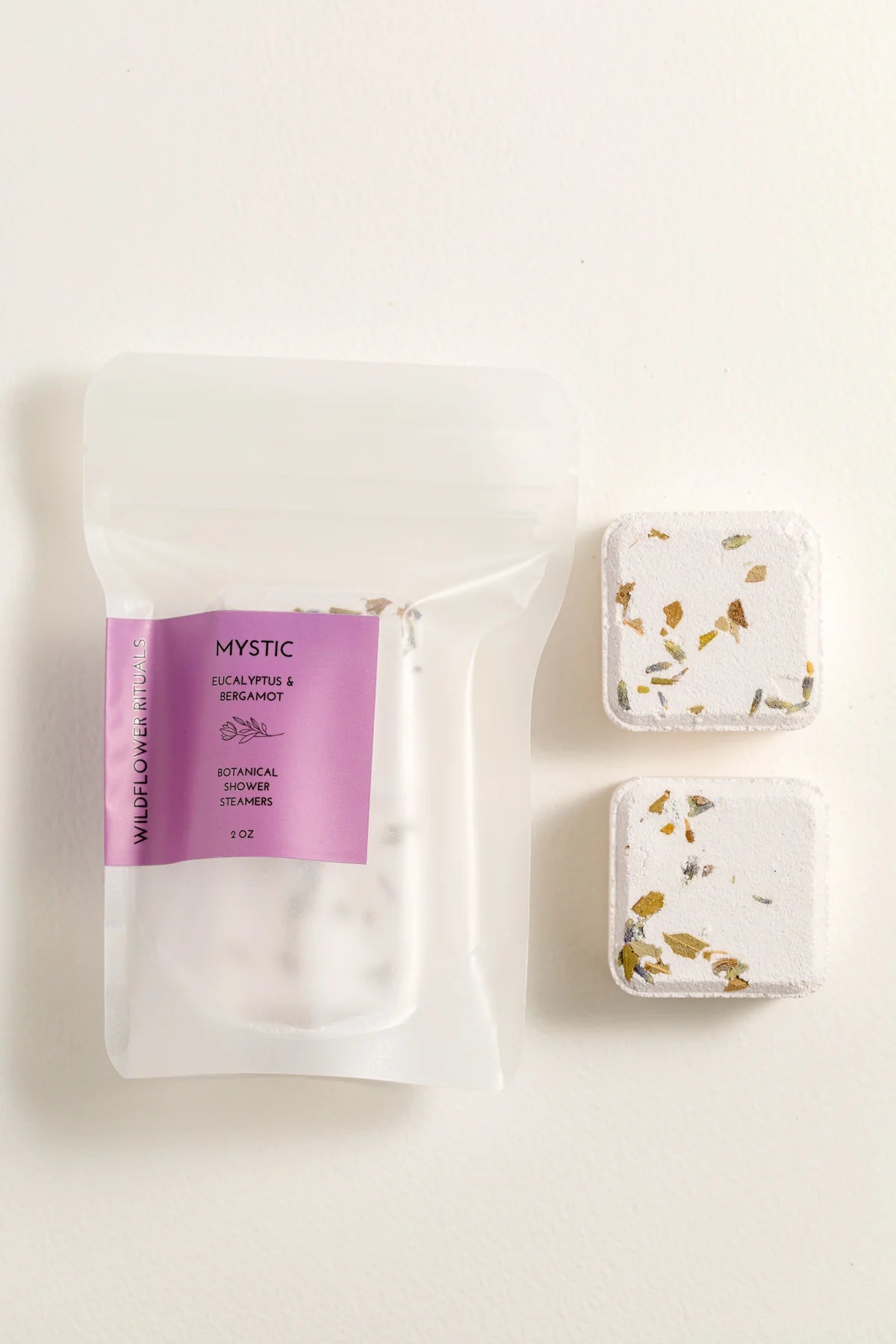 Two small containers with floral designs and a purple labeled package on a white background