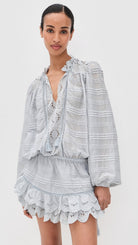 Woman wearing a light gray striped outfit with lace details on a white background
