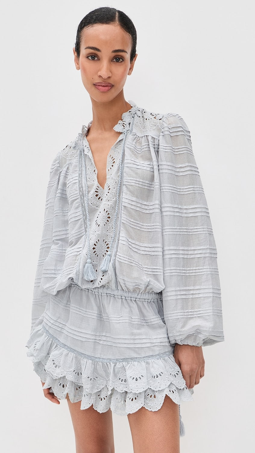 Woman wearing a light gray striped outfit with lace details on a white background