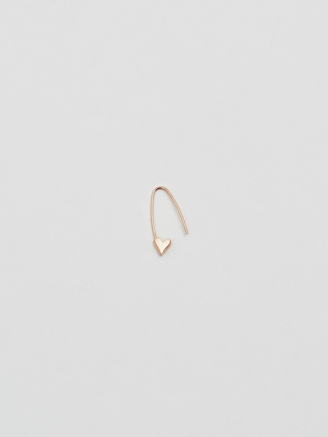 A single 14Kt gold heart safety pin earring on a white background